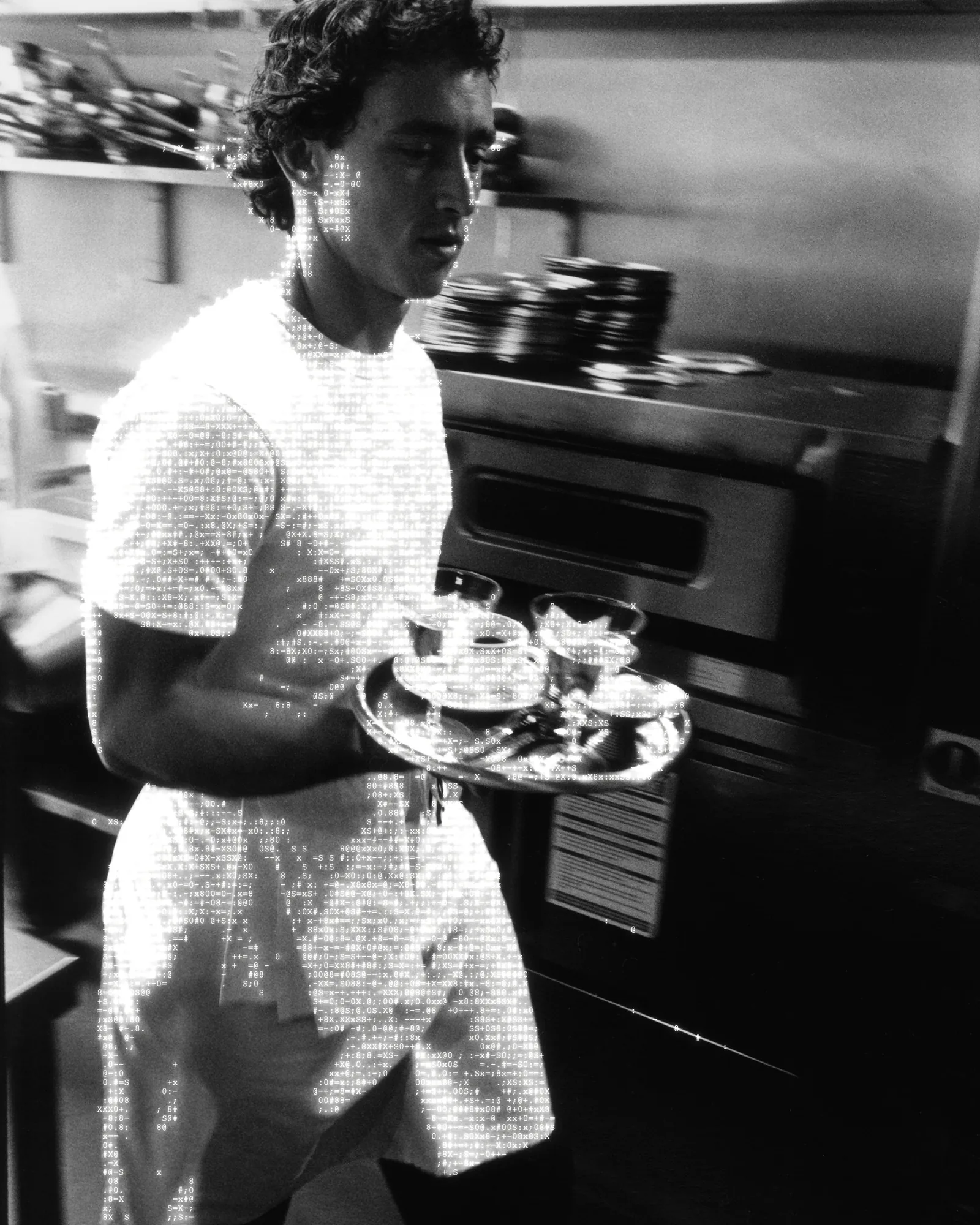 A waiter carries drinks through a restaurant kitchen